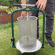 Fruktpress Original 18L En vuxen man använder en cylinderformad fruktpress i rostfritt stål och gröna detaljer utomhus i trädgården